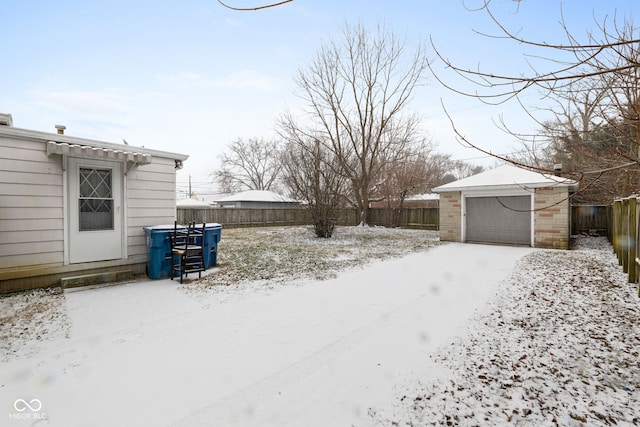 snowy yard featuring an outbuilding and a garage