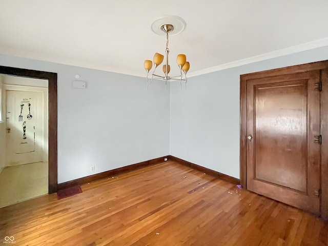 unfurnished dining area with hardwood / wood-style flooring, ornamental molding, and a chandelier