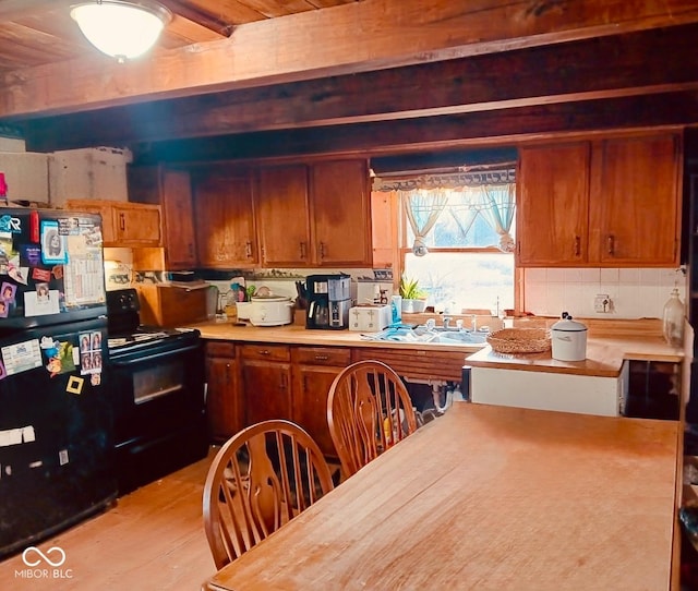 kitchen featuring beam ceiling, sink, light hardwood / wood-style floors, decorative backsplash, and black appliances