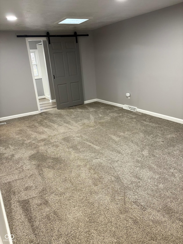 spare room with a barn door and carpet