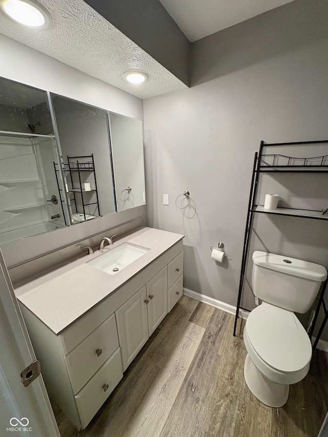 bathroom with hardwood / wood-style flooring, vanity, toilet, and a textured ceiling