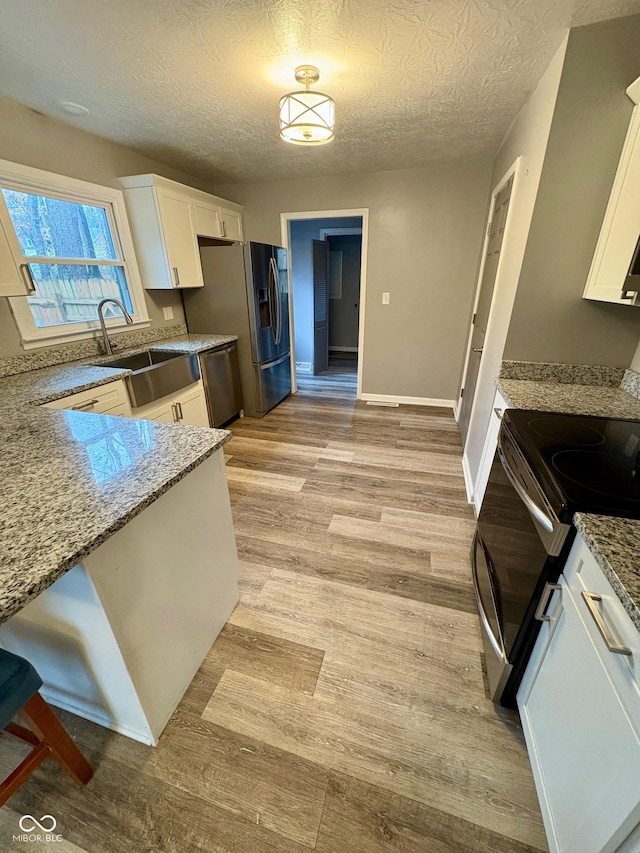 kitchen featuring light stone countertops, sink, white cabinets, and light hardwood / wood-style floors