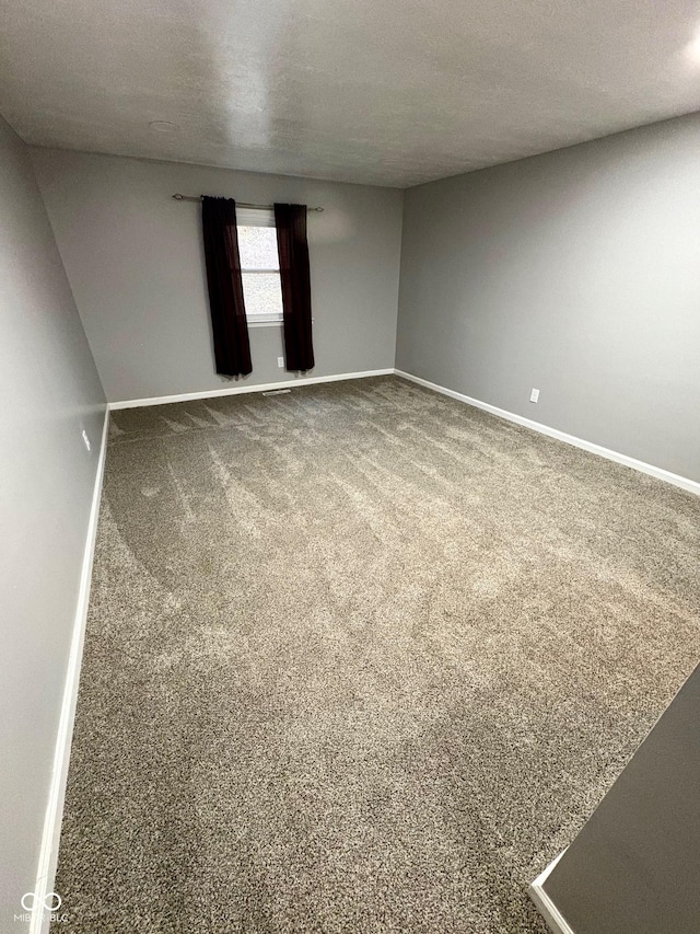 empty room featuring carpet and a textured ceiling