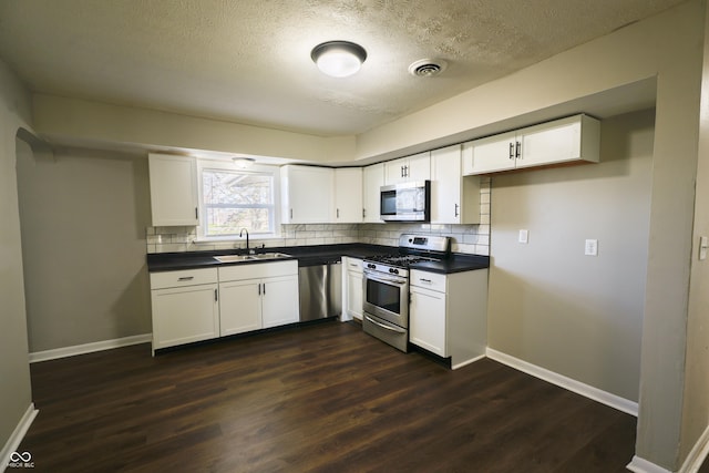 kitchen with dark hardwood / wood-style flooring, tasteful backsplash, stainless steel appliances, sink, and white cabinetry