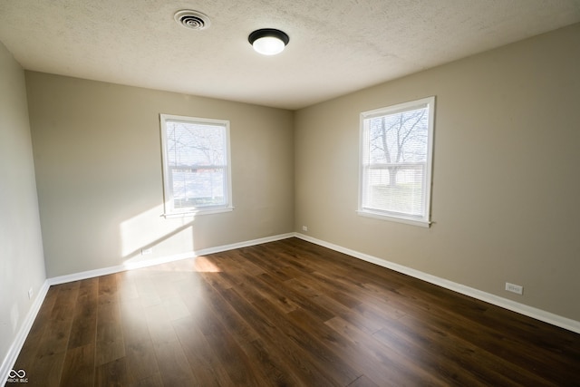 unfurnished room with a textured ceiling and dark hardwood / wood-style flooring