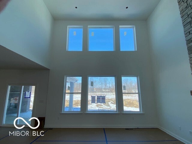 unfurnished living room with a towering ceiling and baseboards