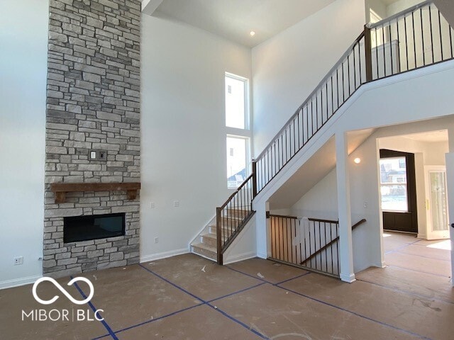 unfurnished living room featuring a towering ceiling, plenty of natural light, and baseboards