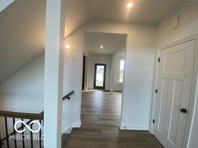 hall with dark wood finished floors, an upstairs landing, and baseboards