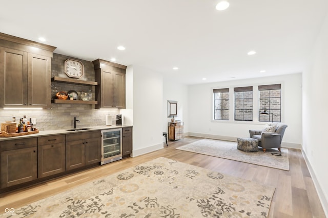 bar featuring tasteful backsplash, beverage cooler, sink, and dark brown cabinets