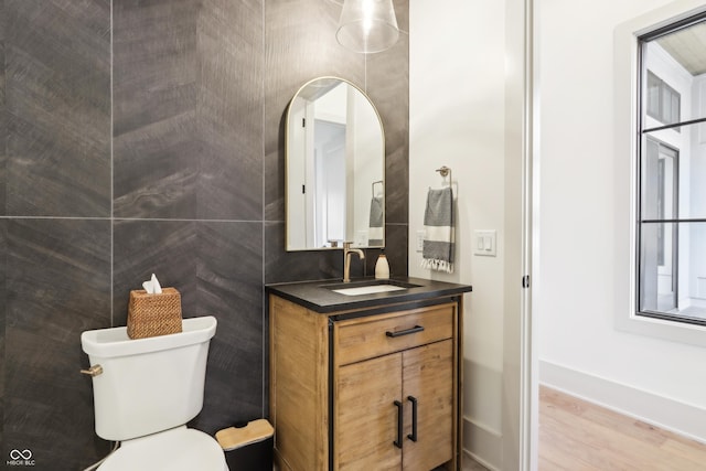 bathroom featuring hardwood / wood-style floors, vanity, tile walls, and toilet