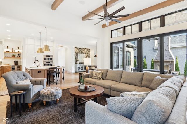 living room featuring wine cooler, sink, beamed ceiling, ceiling fan, and light hardwood / wood-style floors