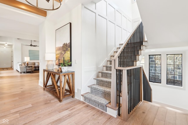 stairs with a towering ceiling, hardwood / wood-style floors, and ceiling fan