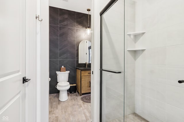 bathroom with tile walls, an enclosed shower, and toilet