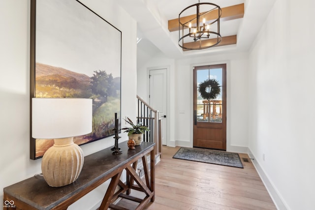 entryway with light hardwood / wood-style floors and a notable chandelier