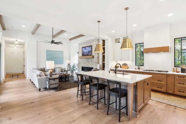 kitchen featuring sink, a breakfast bar area, hanging light fixtures, a center island with sink, and stainless steel gas stovetop