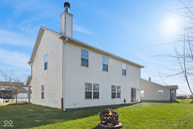 rear view of house with a fire pit and a lawn