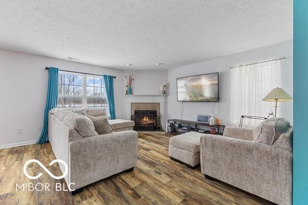 living room featuring a tile fireplace, dark hardwood / wood-style floors, and a textured ceiling