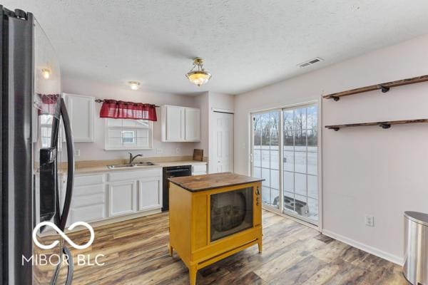 kitchen featuring stainless steel refrigerator, dishwasher, sink, white cabinets, and hardwood / wood-style flooring