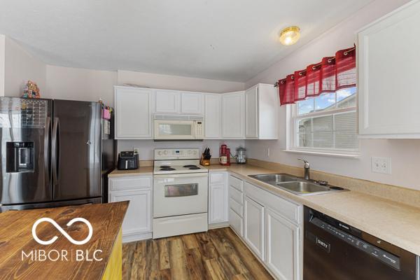 kitchen with sink, white cabinets, and white appliances