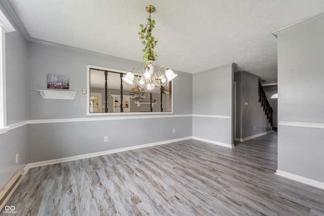 unfurnished dining area with hardwood / wood-style floors, crown molding, a textured ceiling, a baseboard radiator, and a notable chandelier