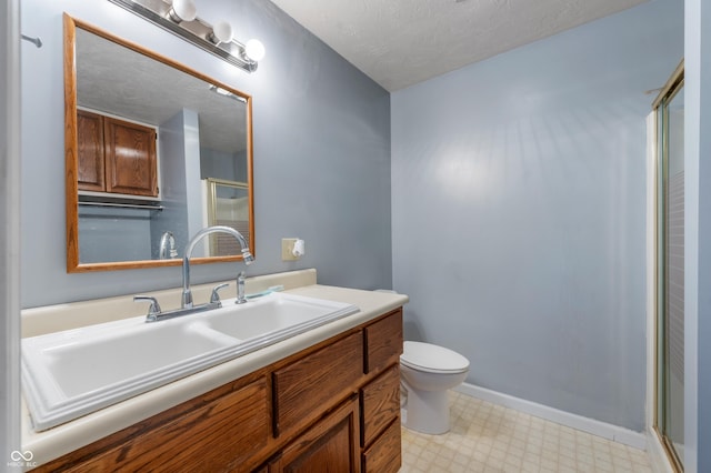 bathroom featuring a textured ceiling, vanity, toilet, and a shower with door