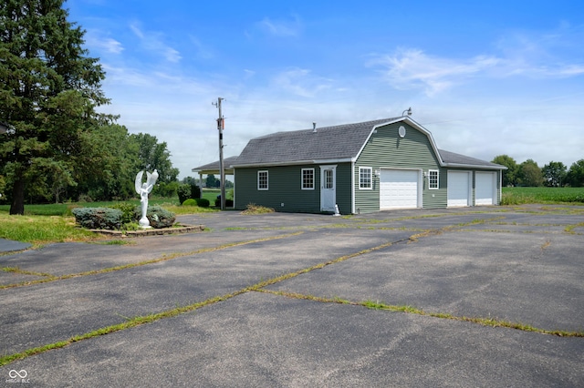 4832 E 200 N, Anderson, IN 46012 - view of front of house with a gambrel roof, an outbuilding, a shingled roof, and driveway