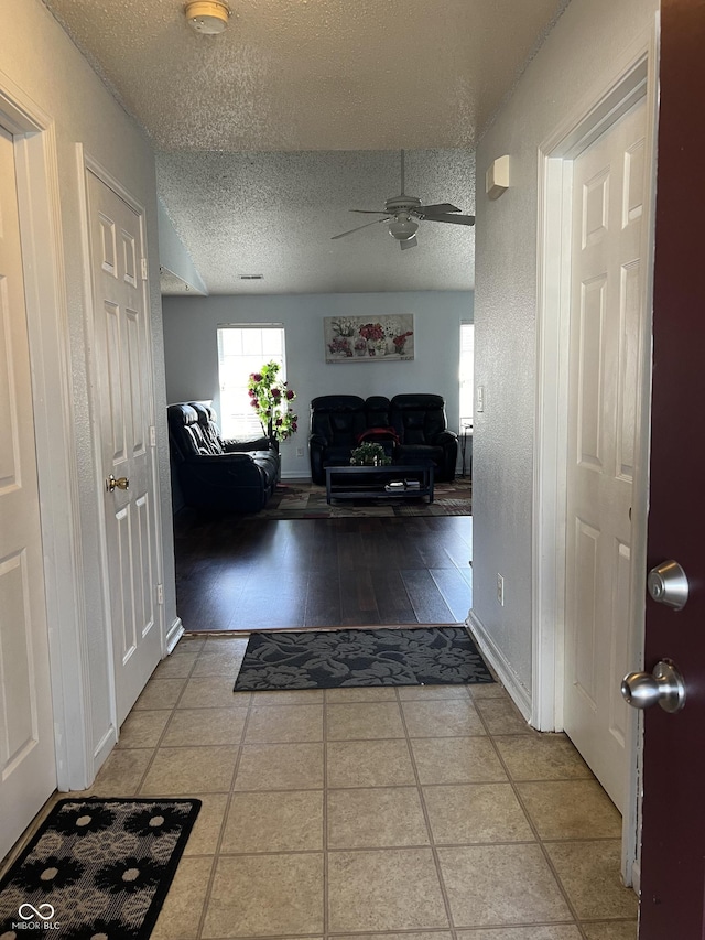 hallway with a textured ceiling and tile patterned floors