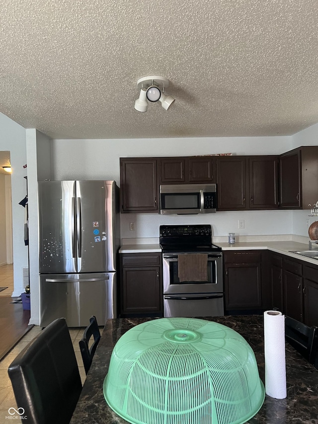 kitchen featuring sink, dark brown cabinets, stainless steel appliances, and a textured ceiling