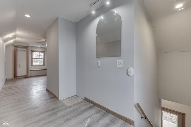 hall featuring a textured ceiling, light hardwood / wood-style flooring, and vaulted ceiling