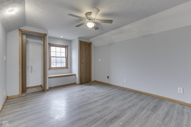 unfurnished bedroom featuring a textured ceiling, ceiling fan, vaulted ceiling, and light wood-type flooring