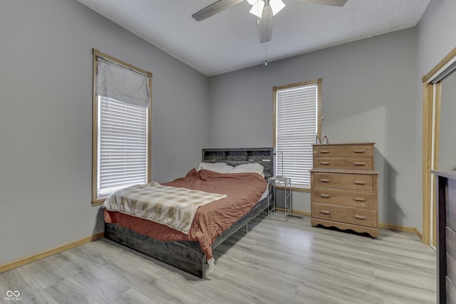 bedroom with ceiling fan, light hardwood / wood-style floors, and a textured ceiling