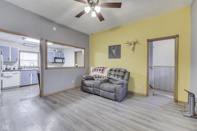 living room featuring ceiling fan, a textured ceiling, and light hardwood / wood-style flooring