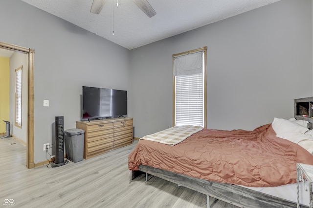 bedroom with ceiling fan, light hardwood / wood-style floors, and a textured ceiling