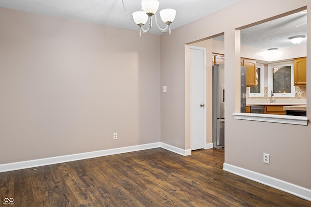 unfurnished room featuring a chandelier, a textured ceiling, dark hardwood / wood-style floors, and sink