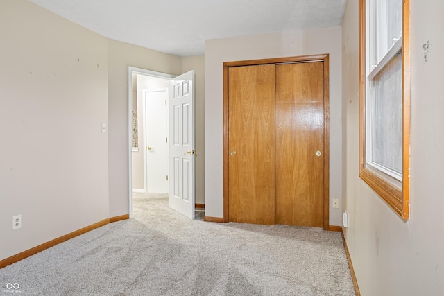 unfurnished bedroom with light carpet and a closet