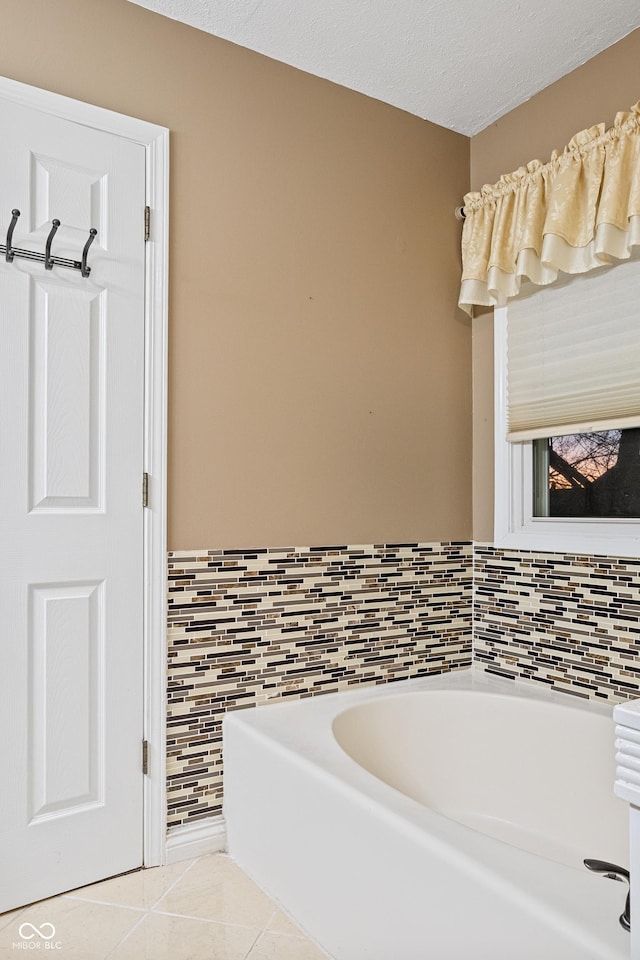 bathroom featuring a washtub, a textured ceiling, and tile patterned floors