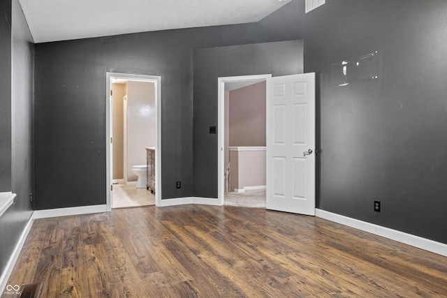 unfurnished bedroom with ensuite bathroom and wood-type flooring