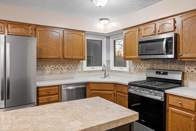 kitchen with a textured ceiling, sink, backsplash, and appliances with stainless steel finishes