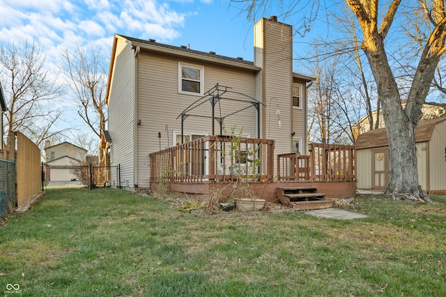 rear view of property featuring a shed, a yard, and a wooden deck