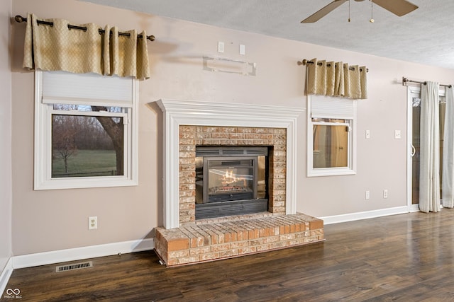 unfurnished living room featuring a fireplace, a textured ceiling, ceiling fan, and dark wood-type flooring