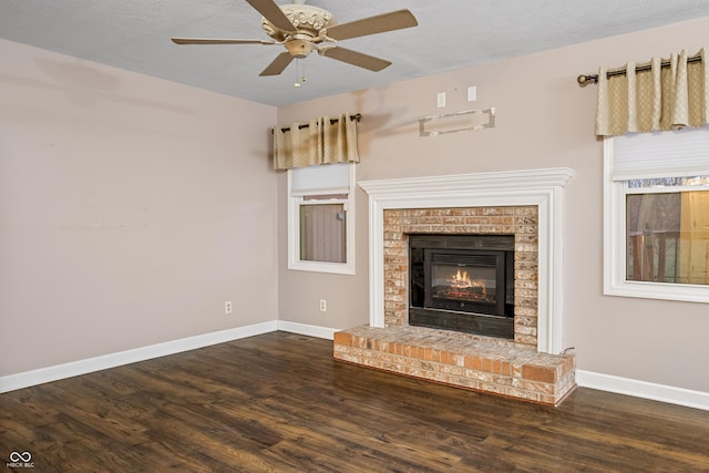 unfurnished living room featuring a textured ceiling, dark hardwood / wood-style floors, a brick fireplace, and ceiling fan