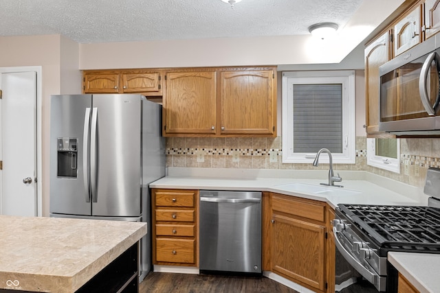 kitchen with sink, dark hardwood / wood-style floors, a textured ceiling, tasteful backsplash, and stainless steel appliances