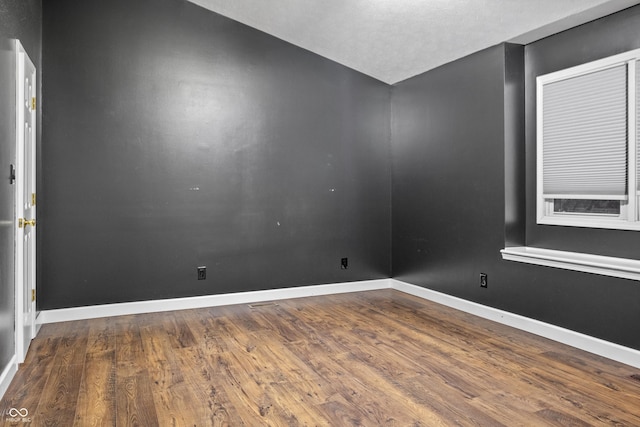 spare room featuring lofted ceiling and wood-type flooring