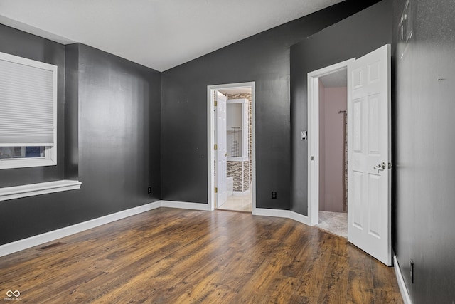 unfurnished bedroom with ensuite bathroom, dark hardwood / wood-style flooring, and vaulted ceiling