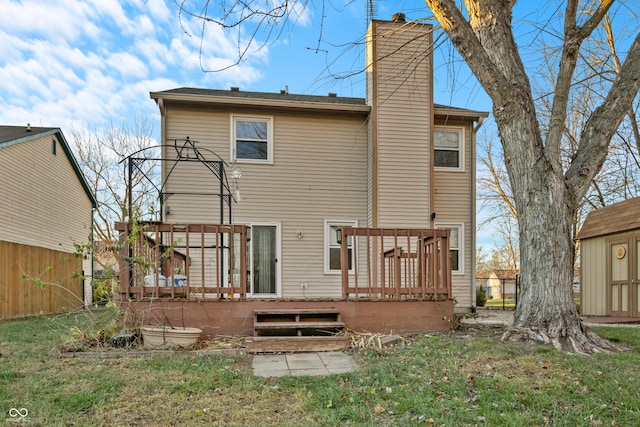 back of property featuring a wooden deck, a yard, and a shed