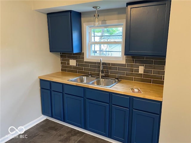 kitchen featuring sink, hanging light fixtures, blue cabinets, butcher block countertops, and decorative backsplash