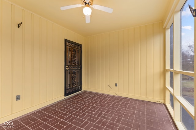 spare room with ceiling fan and wooden walls