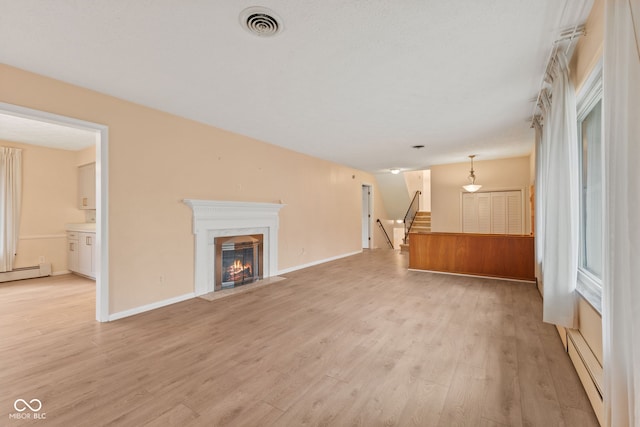 unfurnished living room featuring a fireplace, light hardwood / wood-style flooring, and a baseboard heating unit