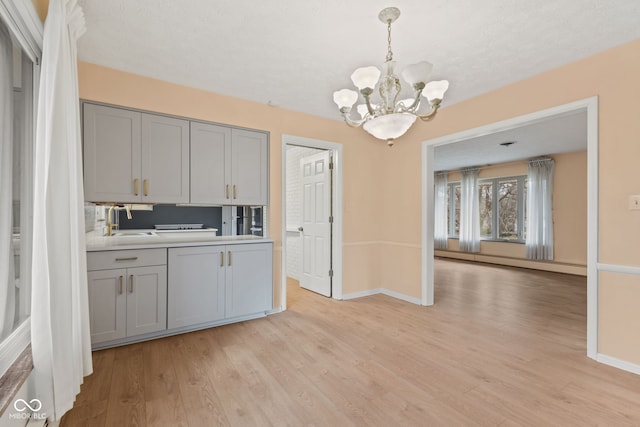 kitchen featuring gray cabinets, light hardwood / wood-style flooring, a baseboard radiator, and a notable chandelier