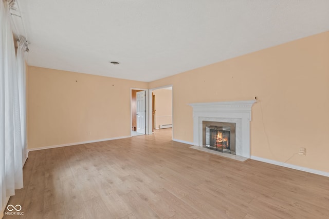 unfurnished living room featuring a high end fireplace, a baseboard radiator, and light wood-type flooring